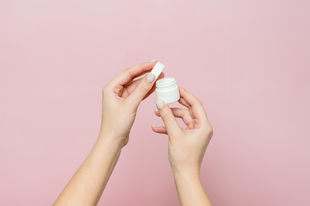 White jar or bottle with cream ointment in woman's hands Facial care bottle with cosmetic product