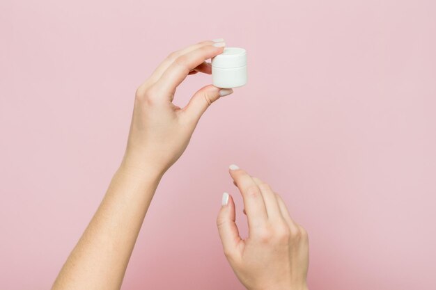 White jar or bottle with cream ointment in woman's hands Facial care bottle with cosmetic product