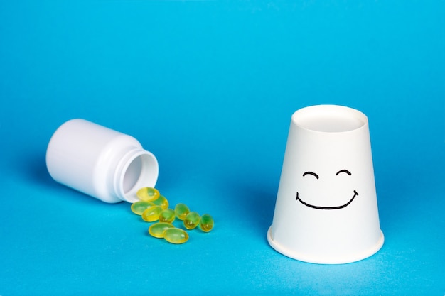 Photo white jar and yellow capsules fish oil pills on a blue background