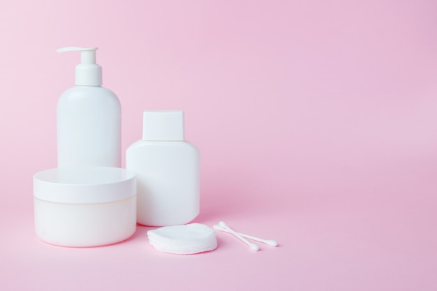 White jars of cosmetics on pink 