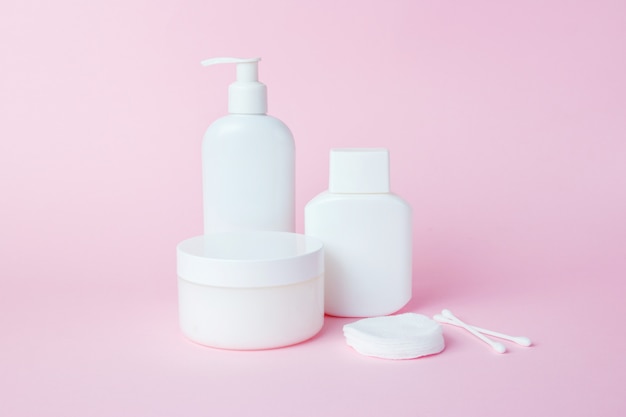 White jars of cosmetics on pink