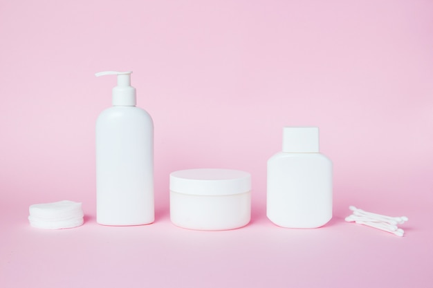 White jars of cosmetics on pink 