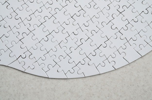 A white jigsaw puzzle in the complete form lies on a treated stone surface. 