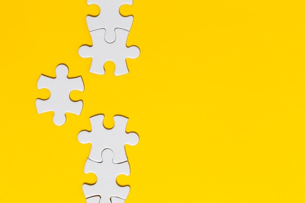 White jigsaw puzzle pieces on a yellow background business solution concept