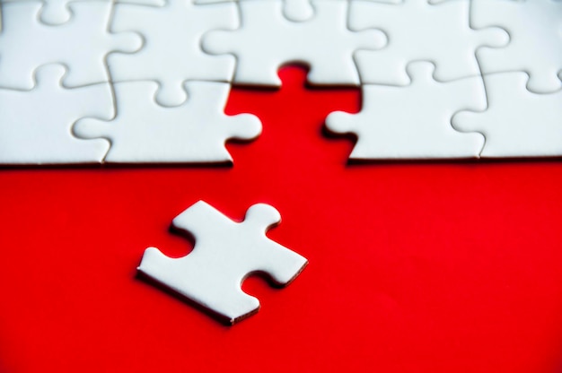 A white jigsaw puzzle separated from the rest on red cover background with customizable space for text or idea Copy space