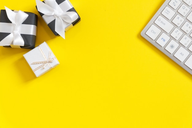 Photo white keyboard and black gift box on yellow background