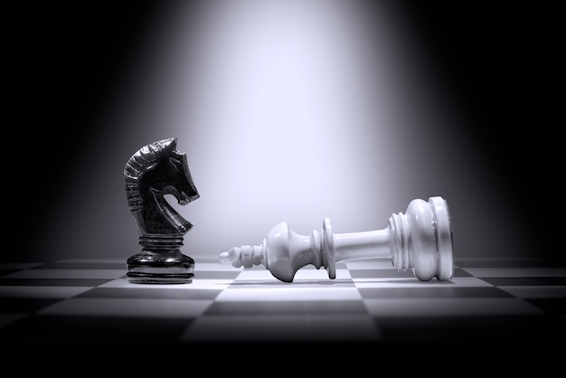 Pezzo degli scacchi re bianco che sconfigge il pezzo degli scacchi del cavaliere nero