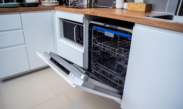 The white kitchen and opened dishwasher with clean dishes