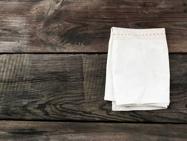 Белое кухонное текстильное полотенце сложено на сером деревянном столе из старых досок