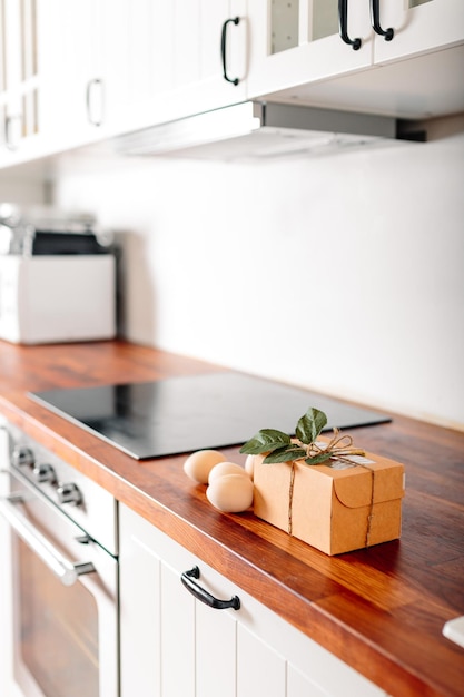Фото Белая кухня с яйцами и подарочной коробкой счастливая пасхальная открытка с деревянными яйцами