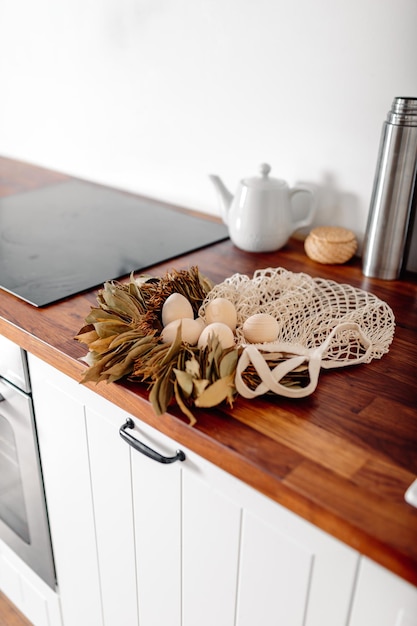 Foto cucina bianca con uova e confezione regalo carta di buona pasqua con uova di legno shopper in rete con uova