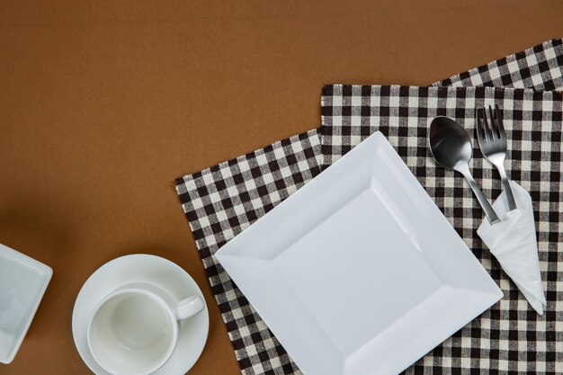White kitchenware set with tablecloth on brown background