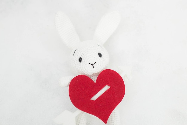 Photo a white knitted rabbit with a red heart and envelope for copy space.