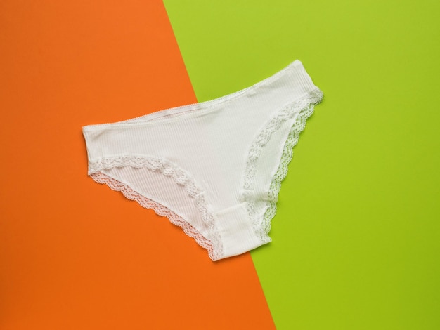 White lace womens panties on an orange and green background Womens underwear