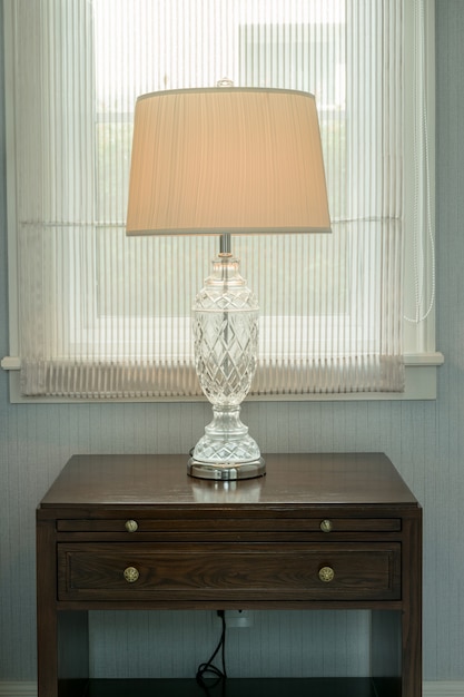 White lamp on bedside wooden table in luxury bedroom