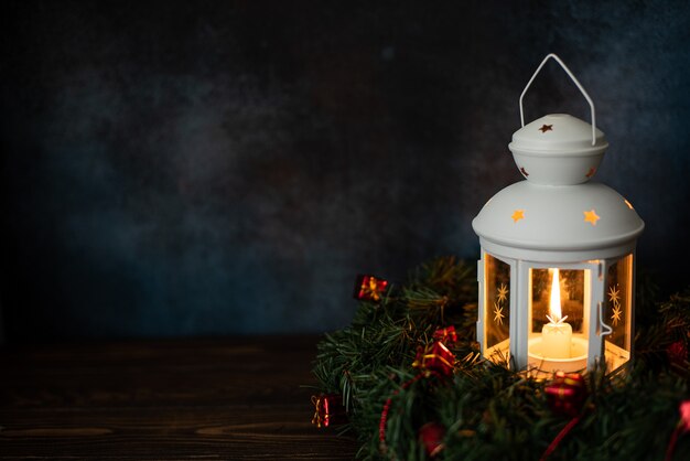 White lantern with a burning candle and fir branches