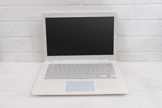 White laptop on the table and white wall behind