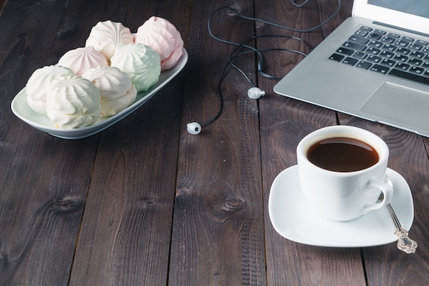 White laptop with coffee cup on old wooden table.