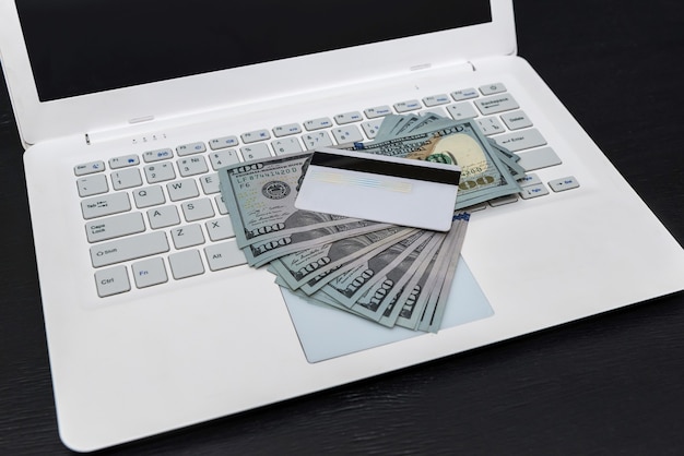 White laptop with dollars and credit card isolated