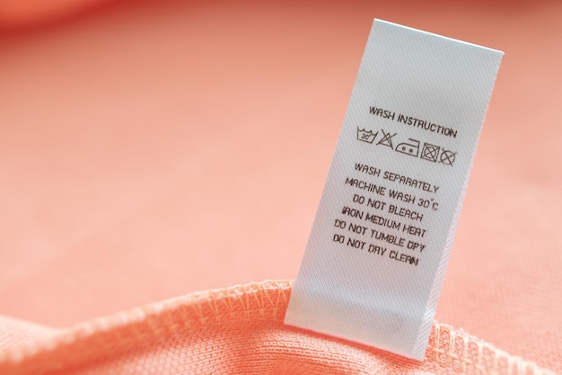 White laundry care washing instructions clothes label on pink cotton shirt