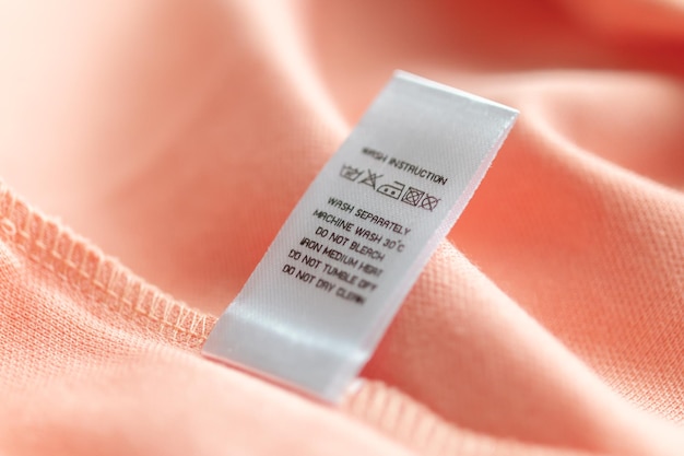 white laundry care washing instructions clothes label on pink cotton shirt