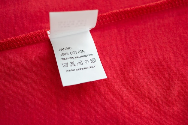 White laundry care washing instructions clothes label on red cotton shirt