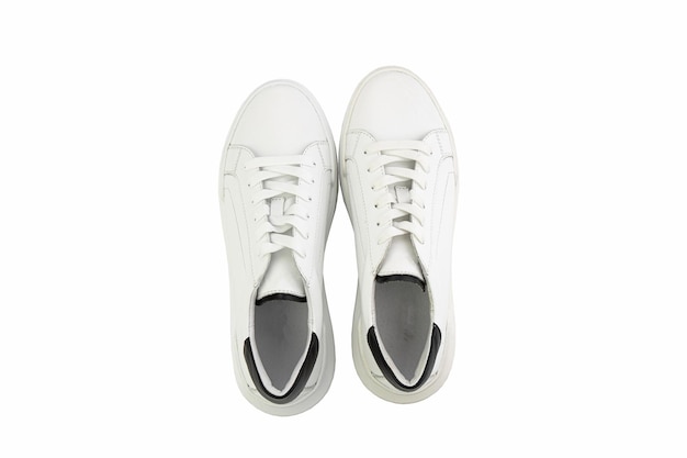 White leather sneakers Casual women's style White lacing and white rubber soles Isolated closeup on white background Top view Fashion shoes