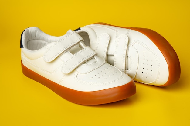 Photo white leather sneakers with advehise fasteners on yellow background