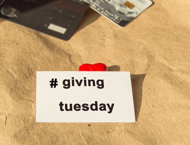 Photo a white letterhead with the hashtag giving on tuesday and bank cards on wrapping paper.