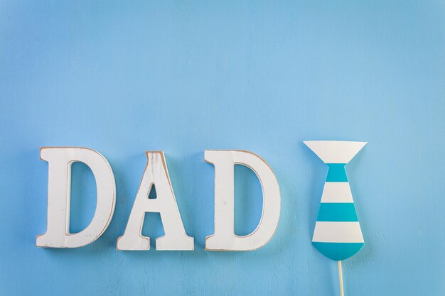 White letters DAD on a painted wood background.