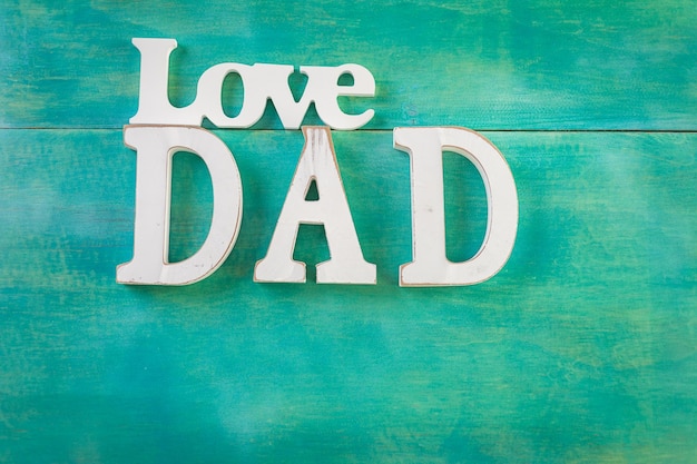white letters dad on a painted wood background.