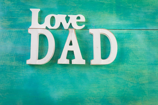 White letters DAD on a painted wood background.