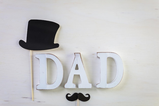 White letters DAD on a painted wood background.