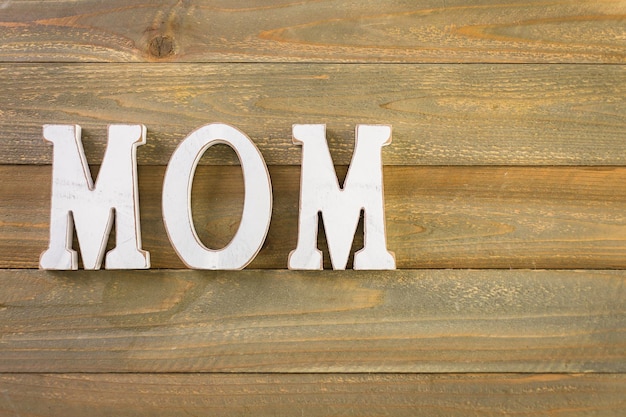 写真 塗られた木の背景に白い文字mom。