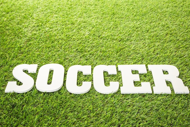 White letters SOCCER on a green grass.