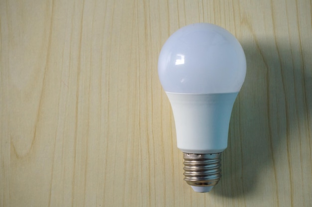 Photo white light bulb on wooden background energy concept