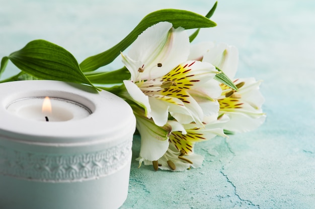 White lit candle, lily fowers