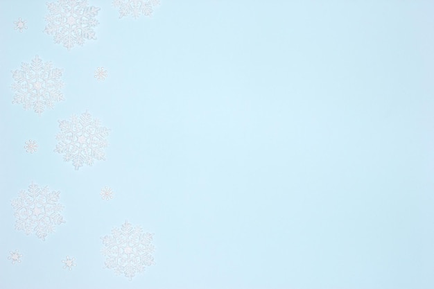 White luminous snowflake frame flat lay on pastel blue background Copy space Simple winter backdrop