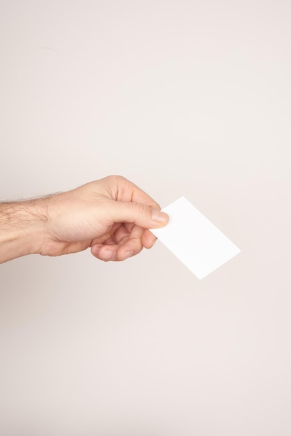 A white male hand holding a business card on a white background.