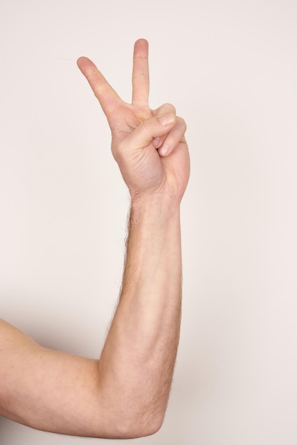 Foto mano maschile bianca che fa un segno di pace su uno sfondo bianco isolato.