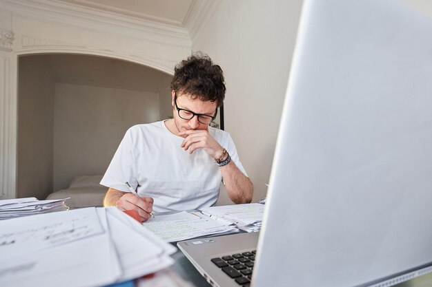 Uomo bianco che studia sul tavolo con un computer portatile