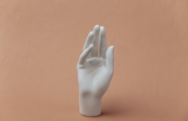 Фото Белый манекен подставка для рук на коричневом фоне
