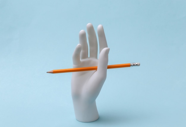 鉛筆と白いマネキンの手は青い背景の上に立っています。知識、教育の概念