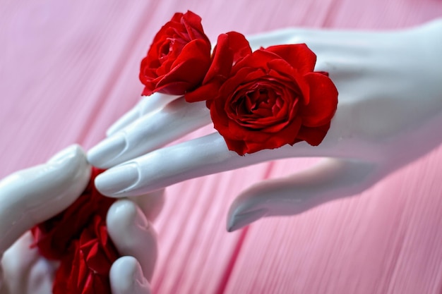 White mannequin hand with red rose flowers