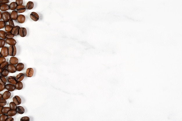 Photo white marble background with scattered coffee beans