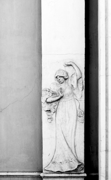 Una statua in marmo bianco di una donna con un abito bianco e un fiocco in testa.