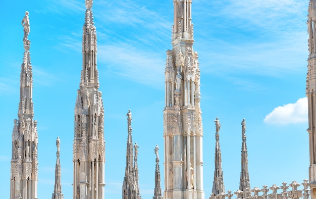 White marble statues on the roof of famous Cathedral Duomo di Milano on piazza in Milan, Italy