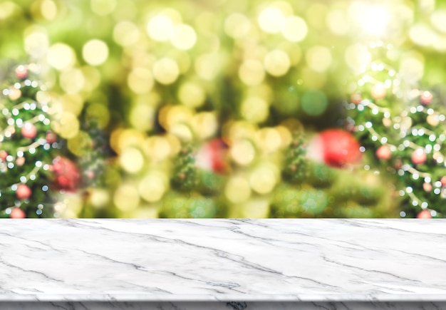 White marble table top with abstract blur christmas tree background with bokeh light