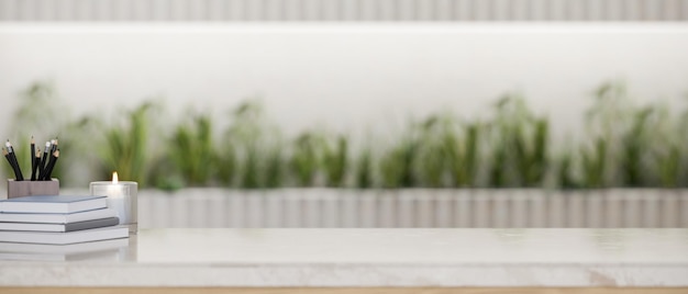 White marble tabletop with stack of book pencils candle and copy space over blurred background