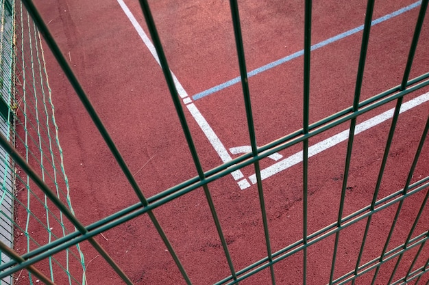 white marking lines of outdoor basketball court fenced with protective metal fence